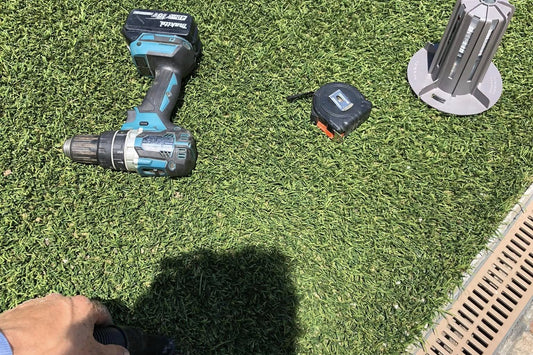 Termite bait station install kit on artificial turf: drill, tape measure and station, during a Webenex install