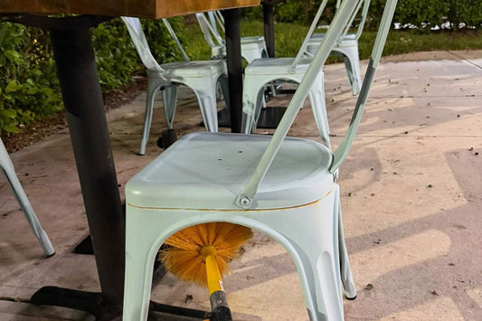 Webenex pole brush clearing webs under a restaurant patio chair after close
