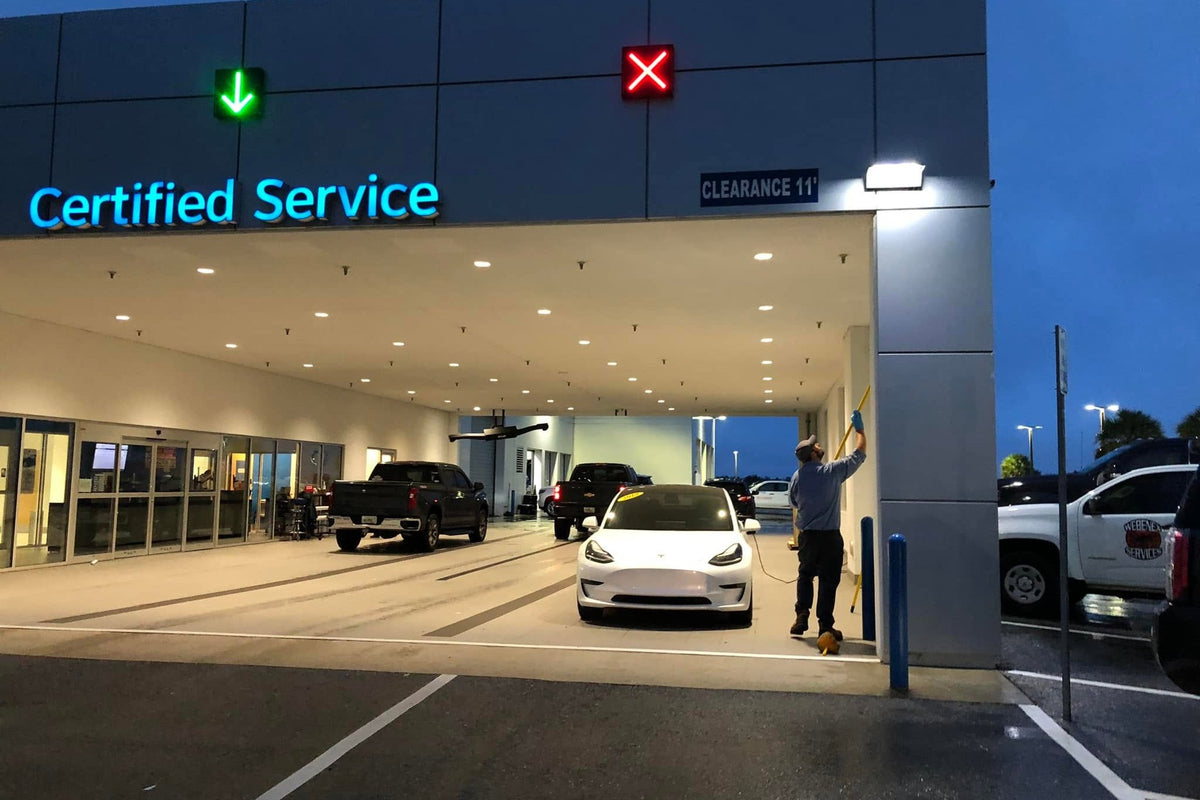 Webenex technician de-webbing a car dealership's service bay at dusk, with the company truck behind