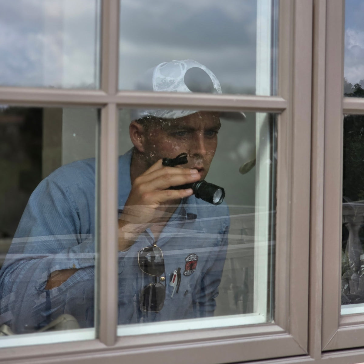 Kevin Sukovich of Webenex Services inspecting a Clermont, FL home through a window with a flashlight