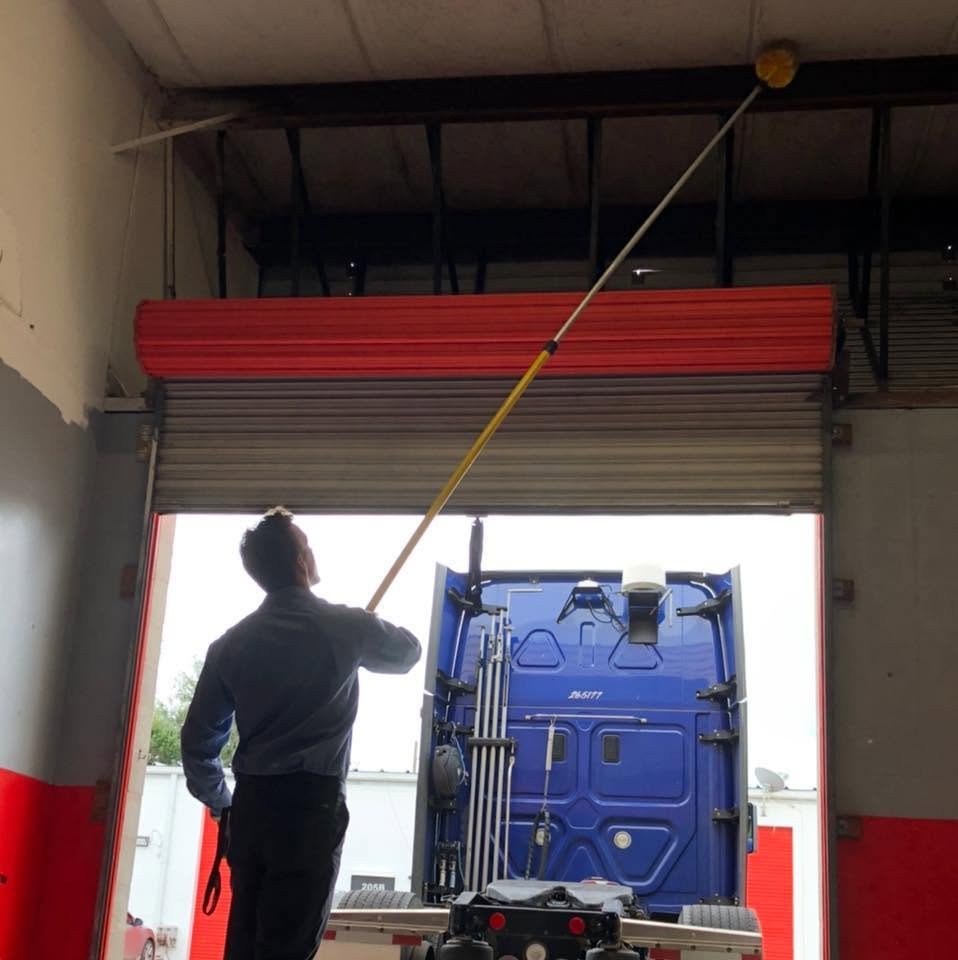 Webenex technician de-webbing the ceiling of a warehouse bay by the roll-up door